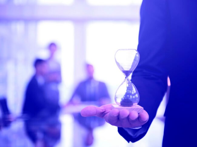 Businessman holding an hour glass, signifies the importance of being on time