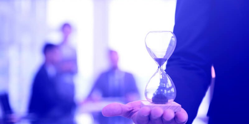 Businessman holding an hour glass, signifies the importance of being on time